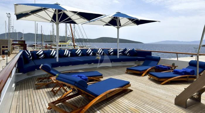a deck with lounge chairs and umbrellas on it aboard THE MERCY BOYS Yacht for Sale