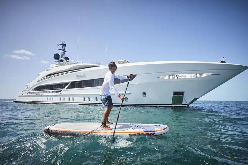 a person on a surfboard next to a boat aboard ARKADIA Yacht for Charter