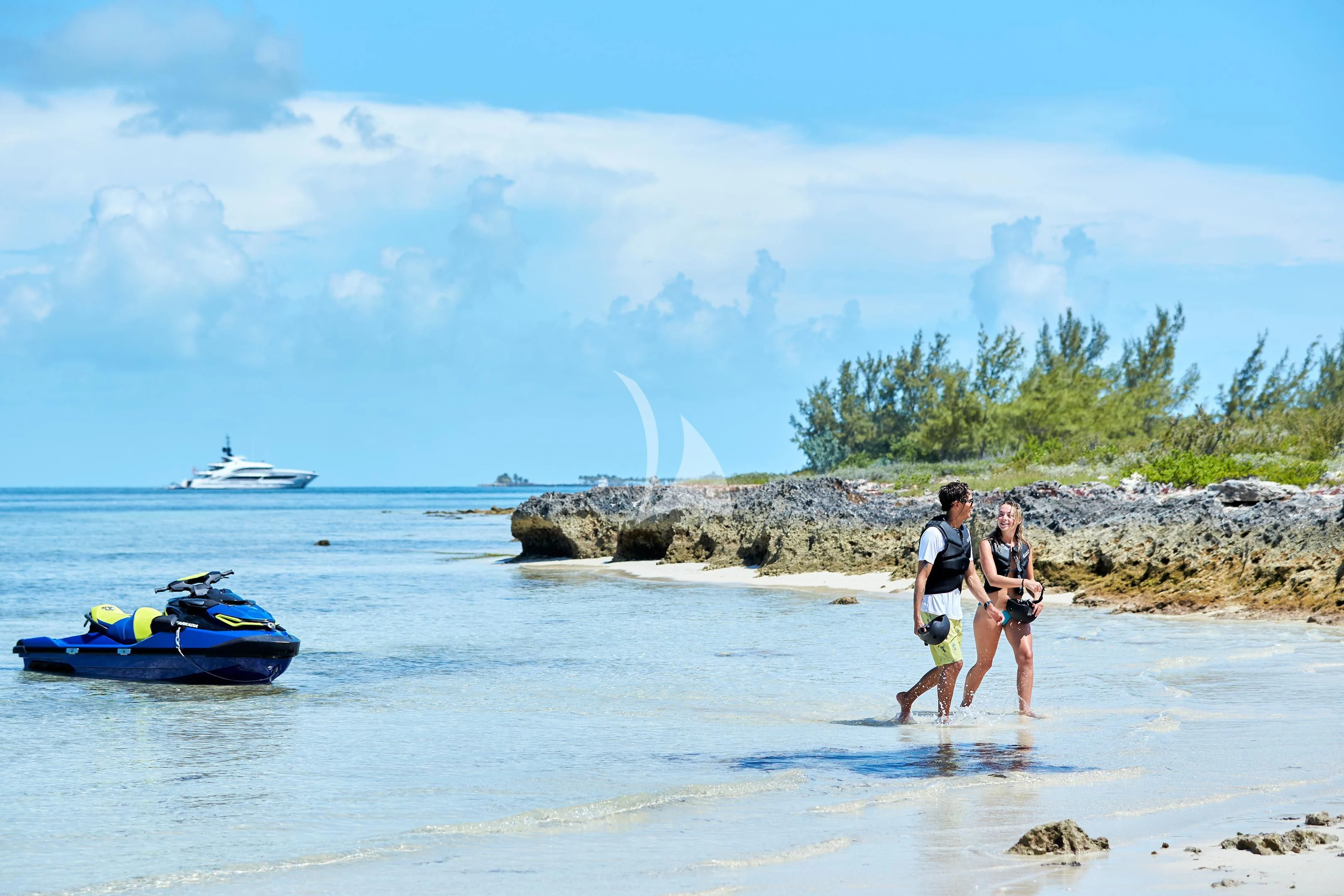 a man and woman walking on a beach with a waterfall in the background aboard ARKADIA Yacht for Charter