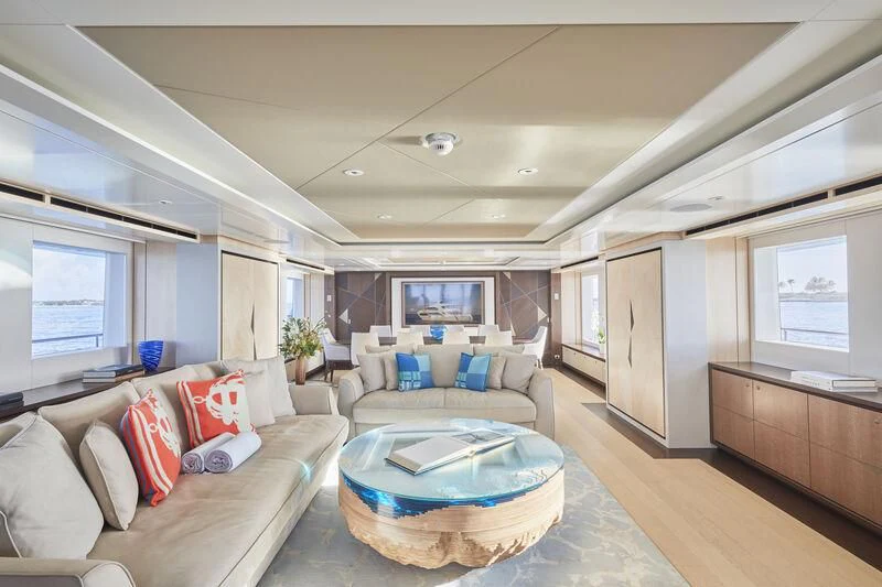 a living room with a large blue couch and a large window aboard ARKADIA Yacht for Charter