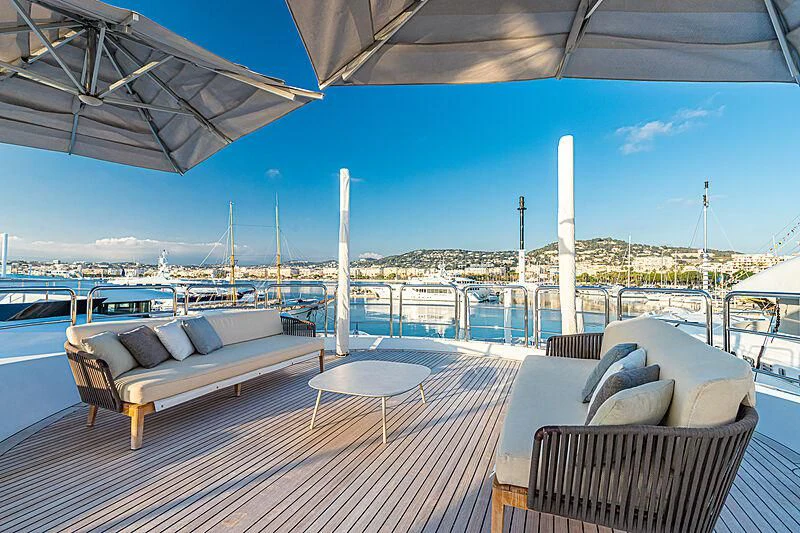 a deck with a table and chairs on it aboard BOMBAY Yacht for Sale