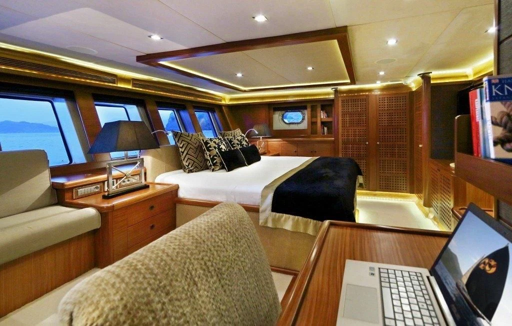 a bedroom with a laptop and a bed aboard DAIMA Yacht for Sale