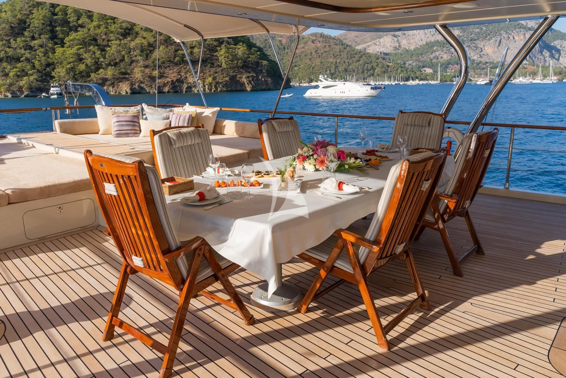 a table set with chairs and a view of a lake aboard DAIMA Yacht for Sale