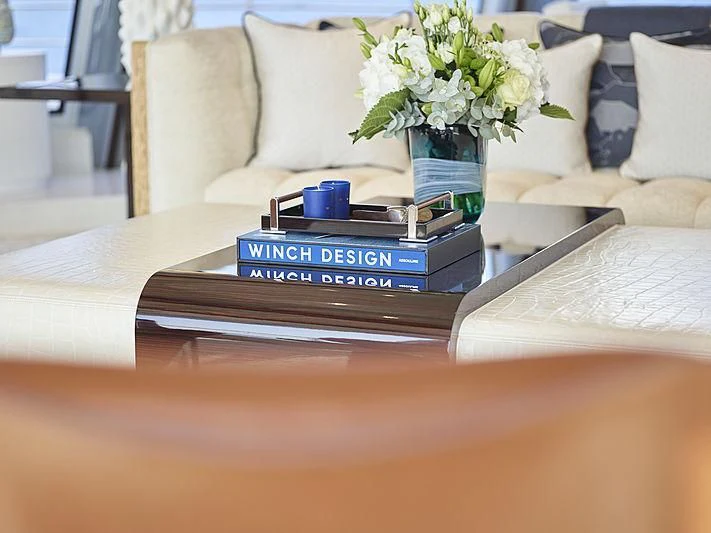 a table with a remote control and a vase of flowers on it aboard EXCELLENCE Yacht for Sale
