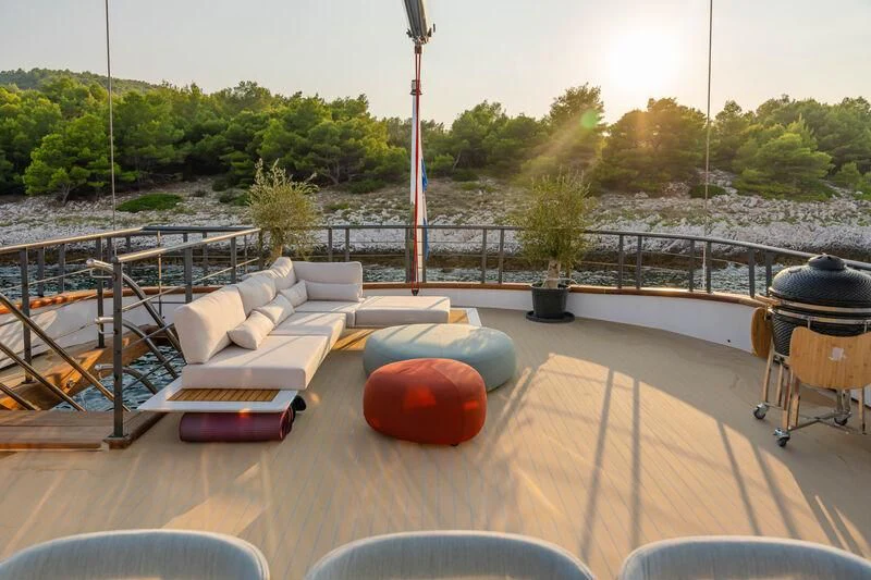 a deck with a couch and a table with a view of a lake aboard ANETTA Yacht for Charter
