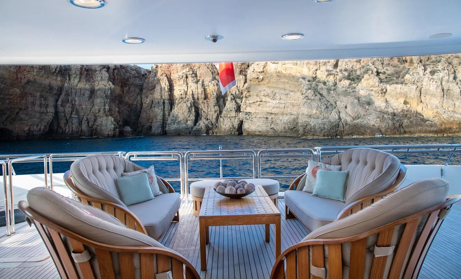a table and chairs on a deck overlooking a body of water aboard IRAVATI Yacht for Sale