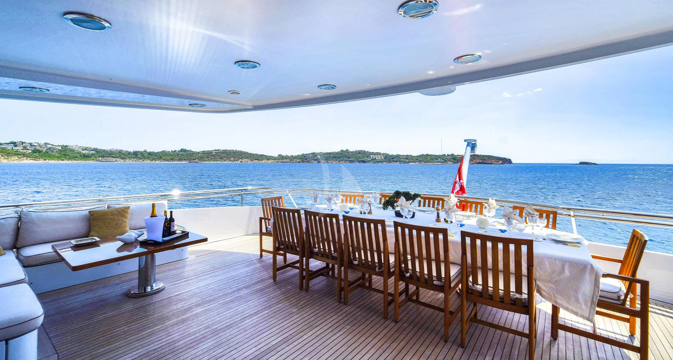 a deck with chairs and tables on it by a body of water aboard IRAVATI Yacht for Sale