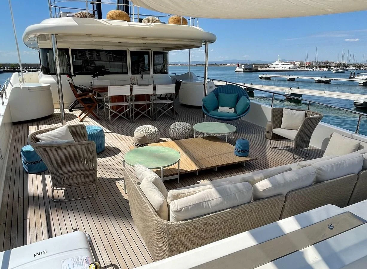 a deck with chairs and tables on it aboard BIM Yacht for Sale