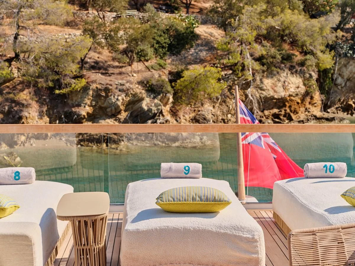 a pool with a flag and a beach and trees in the background aboard RARE DIAMOND Yacht for Sale