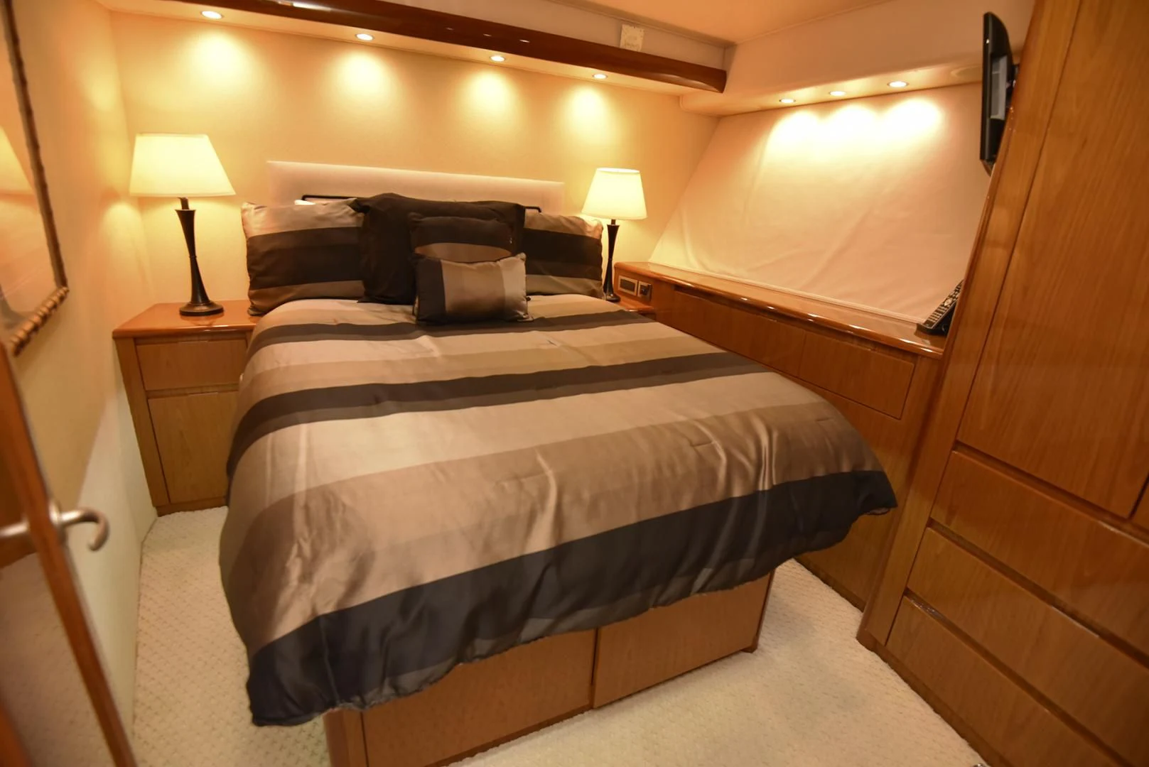 a bed with a black and white comforter and a night stand aboard SALTY K Yacht for Sale