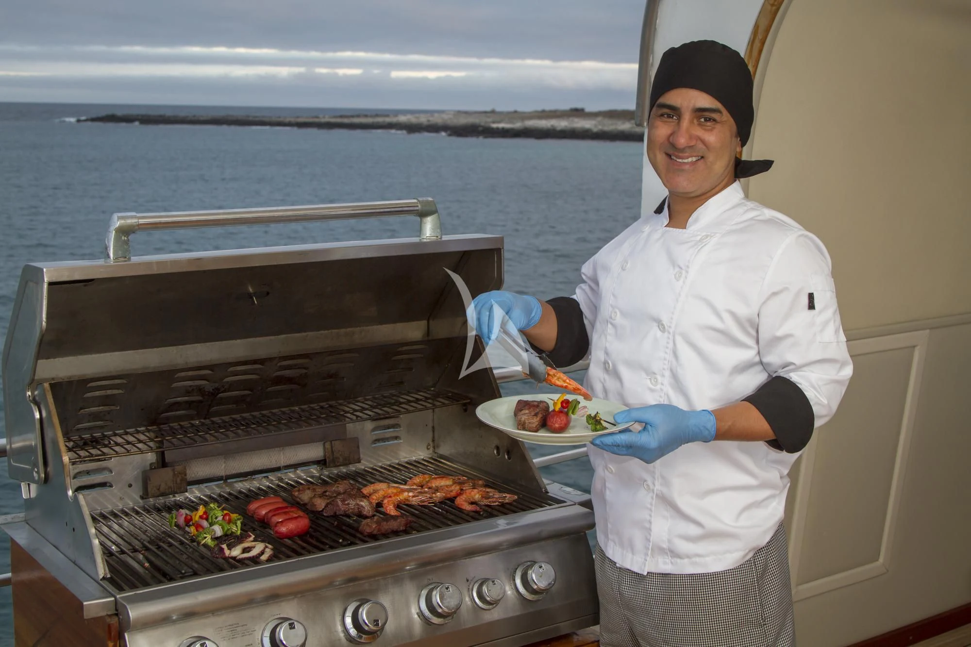 a chef holding a plate of hot dogs aboard INTEGRITY Yacht for Sale
