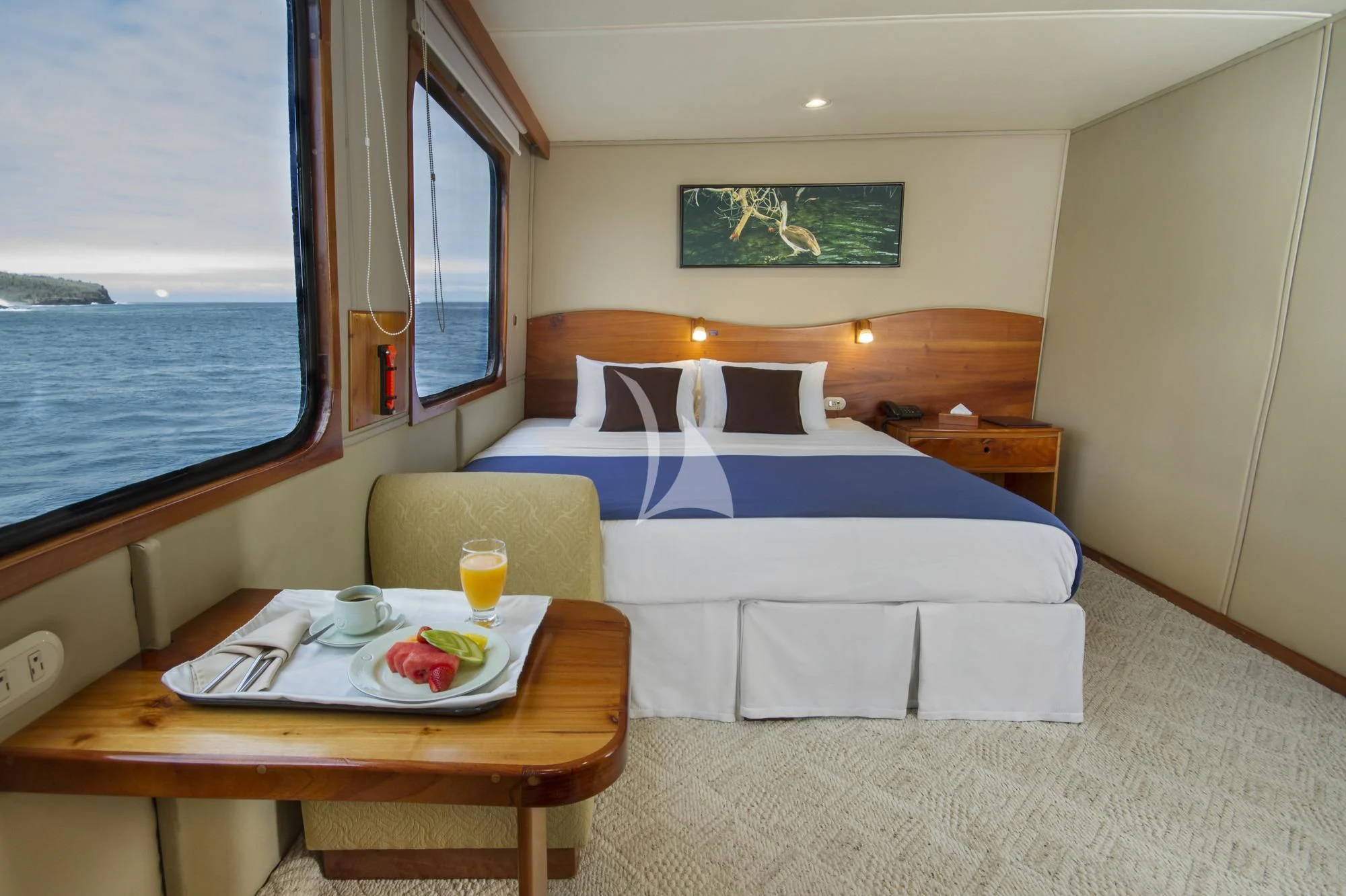 a bed with a table and a glass of juice on a table aboard INTEGRITY Yacht for Sale