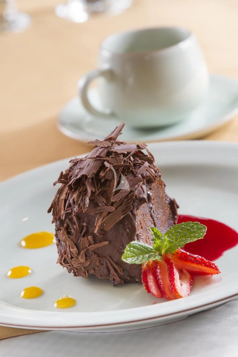 a piece of chocolate cake with strawberries and a cup of coffee aboard INTEGRITY Yacht for Sale