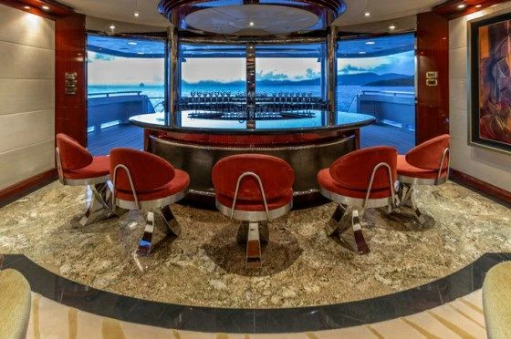 a bar with red chairs and a table with red chairs aboard DRIVEN Yacht for Sale