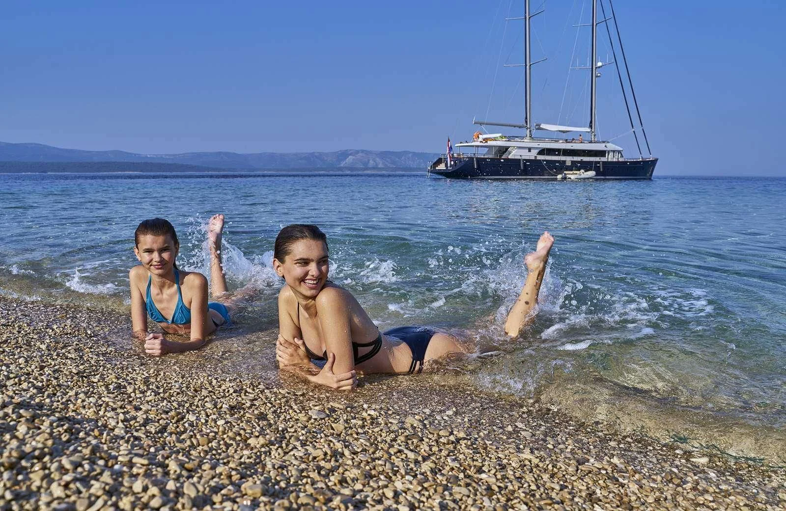 two children sitting on a beach aboard DALMATINO Yacht for Sale