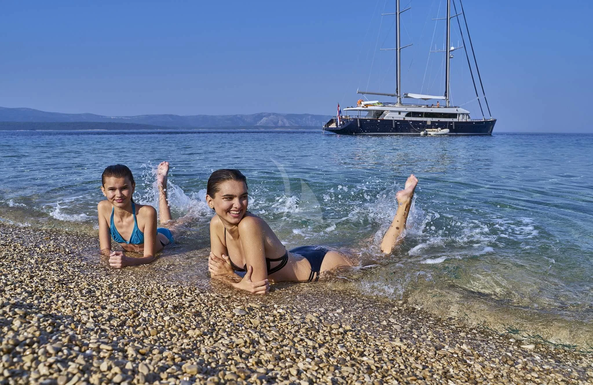 two people sitting on a beach aboard DALMATINO Yacht for Sale