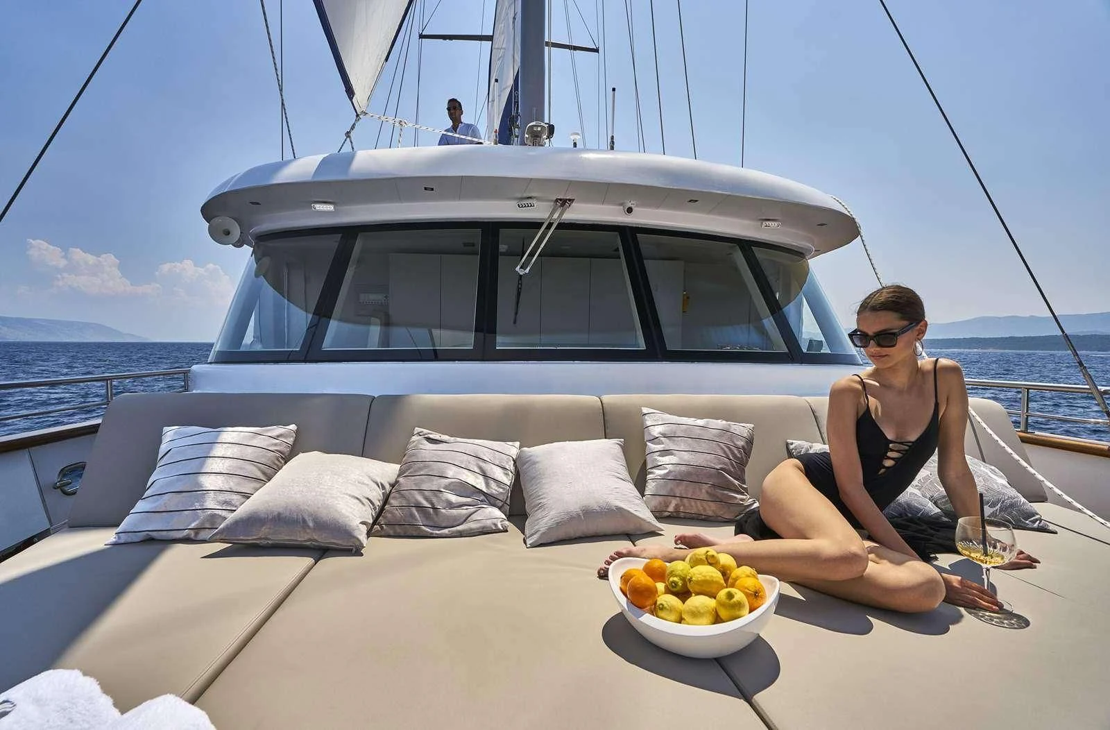 a person sitting on a couch on a boat with a bowl of fruit aboard DALMATINO Yacht for Sale