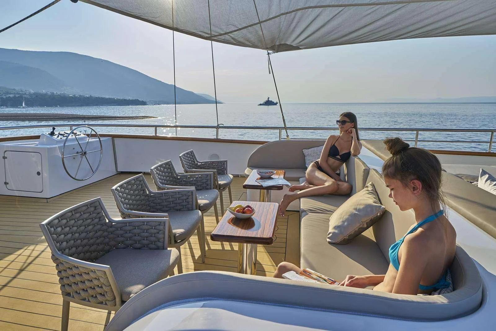 a person sitting on a lounge chair on a deck with a person lying on the floor aboard DALMATINO Yacht for Sale