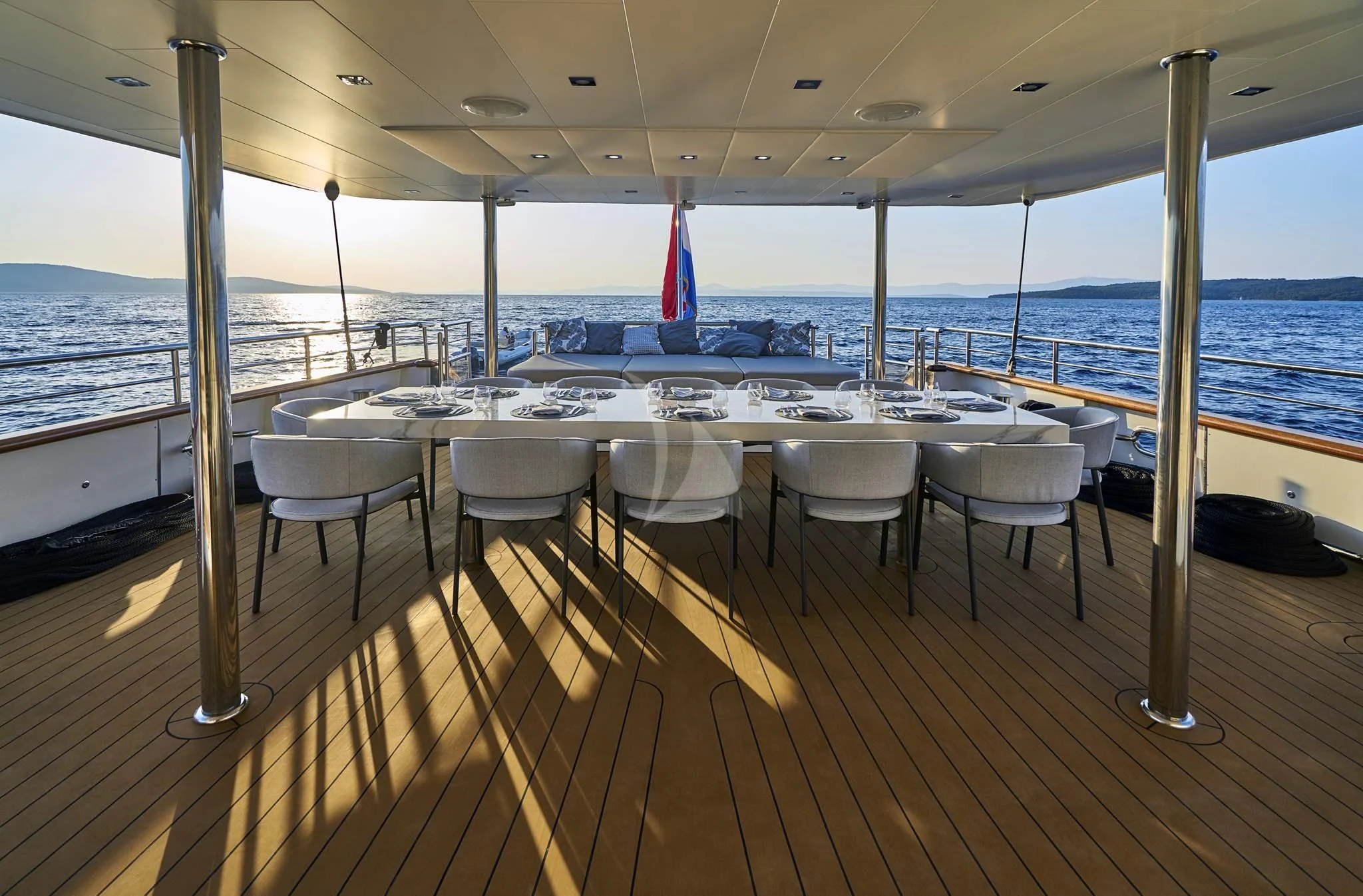 a deck with a table and chairs aboard DALMATINO Yacht for Sale