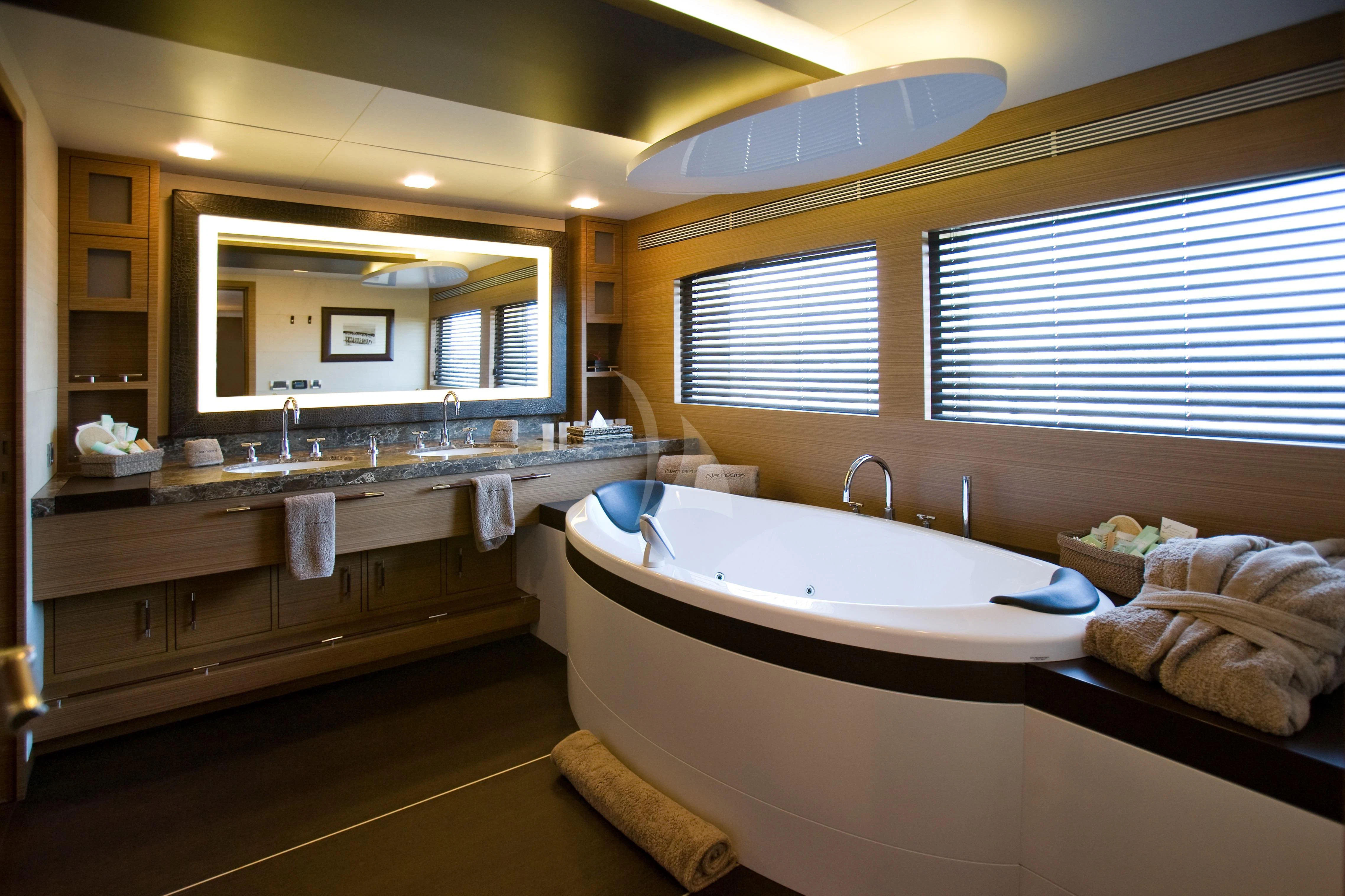 a bathroom with a tub sink and a large mirror aboard QHT Yacht for Sale