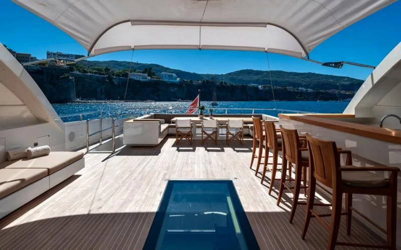 a deck with chairs and tables on it by a large body of water aboard QHT Yacht for Sale