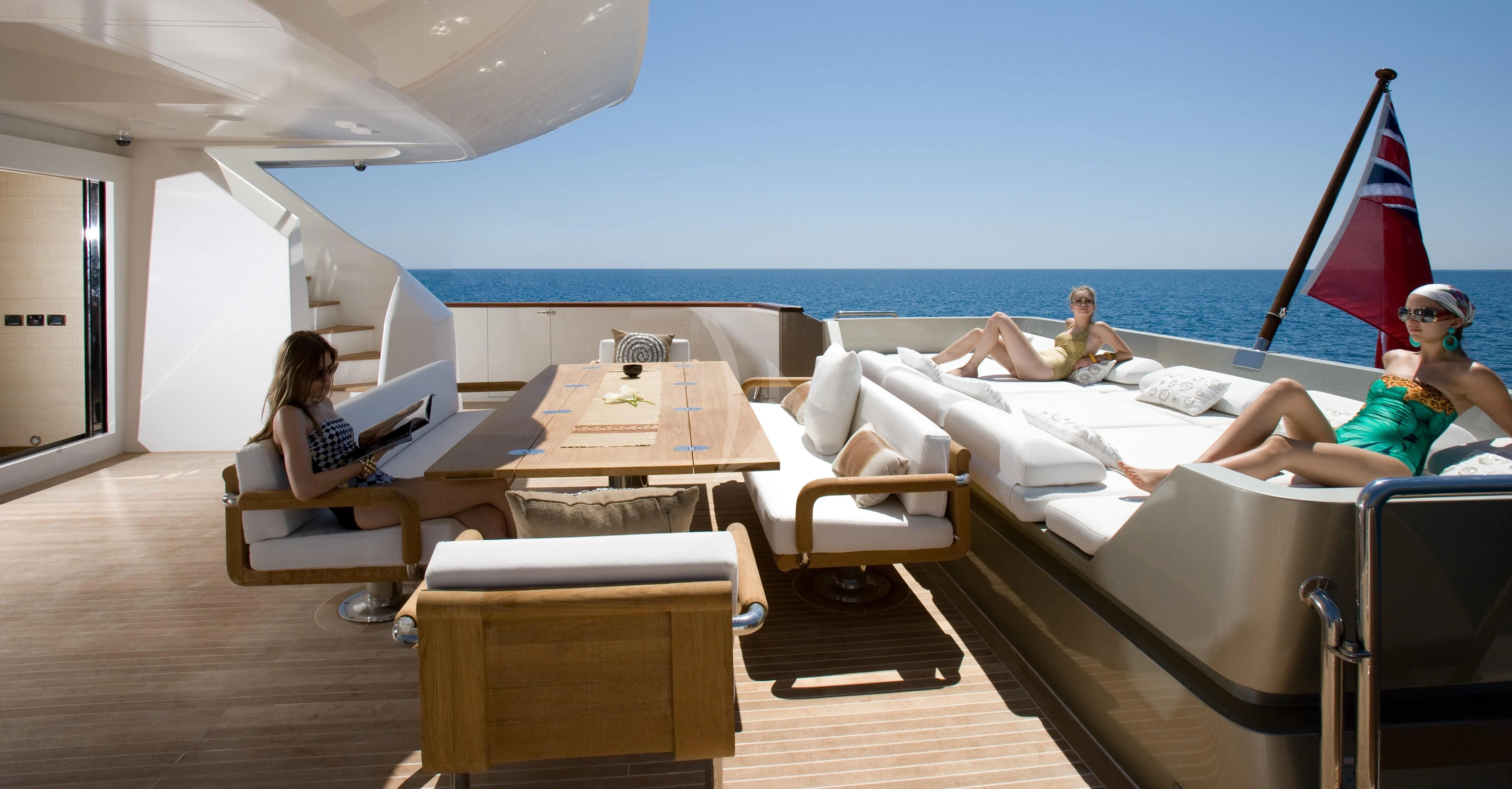 a group of people sitting on a couch in a room with a large body of water and a aboard QHT Yacht for Sale