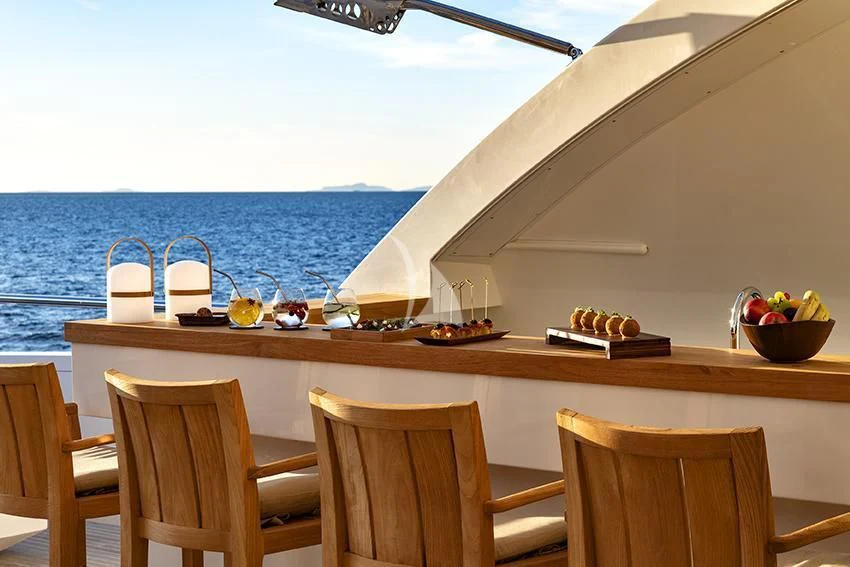 a table with chairs and a view of the ocean aboard QHT Yacht for Sale