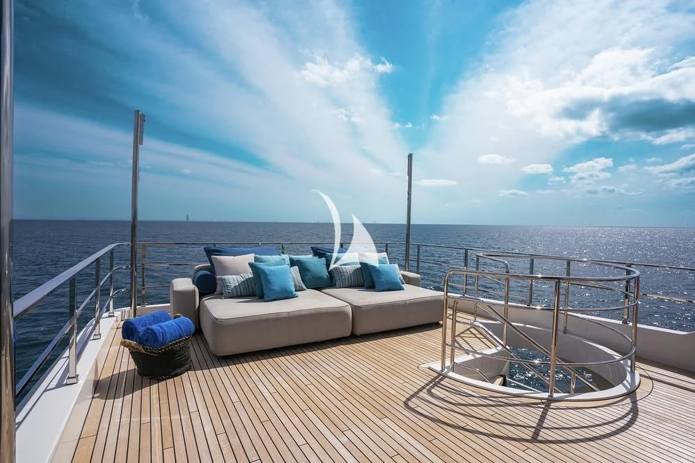 a couch and a chair on a boardwalk by the water aboard JYC Yacht for Sale