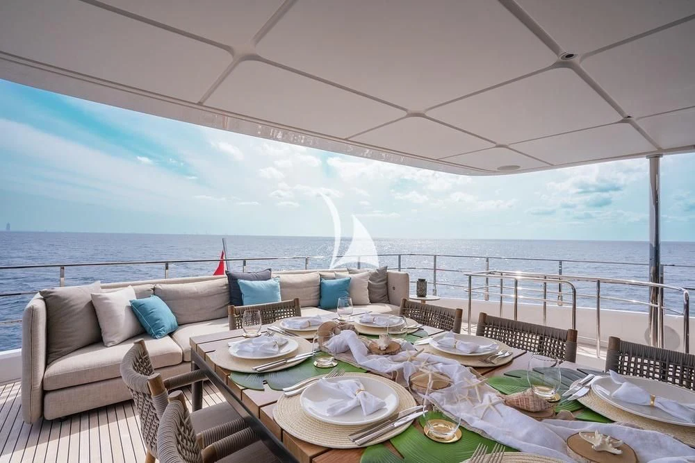 a large white tent with a table and chairs and a view of the ocean aboard JYC Yacht for Sale