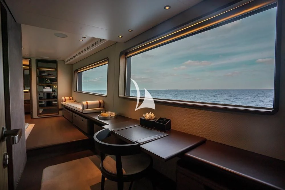 a room with a large window and a table with chairs and a view of the ocean aboard JYC Yacht for Sale