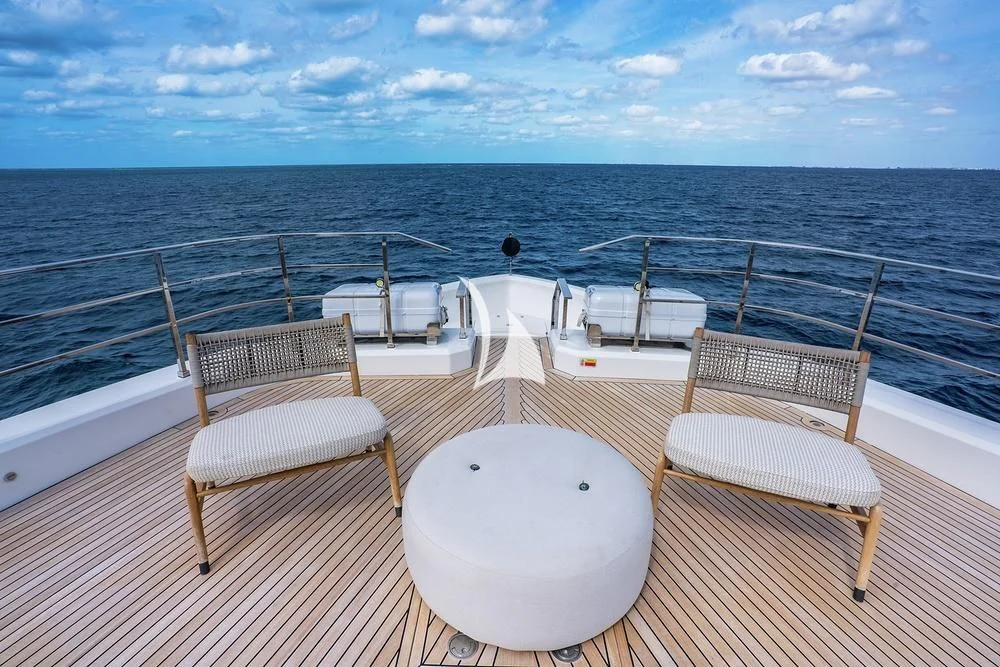 a deck with chairs and tables on it by the ocean aboard JYC Yacht for Sale