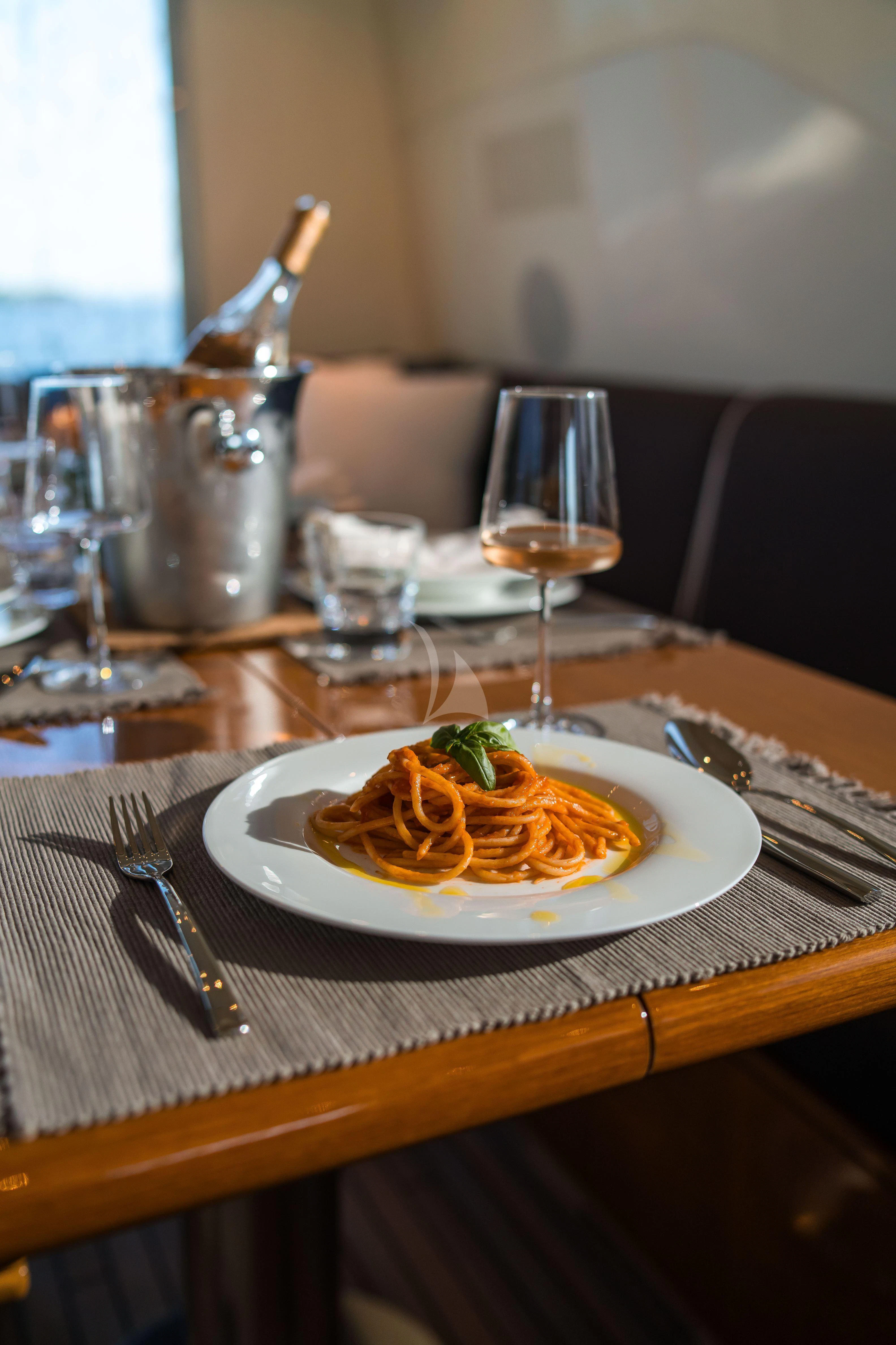 a plate of food and a glass of wine on a table aboard TOBEKA Yacht for Sale