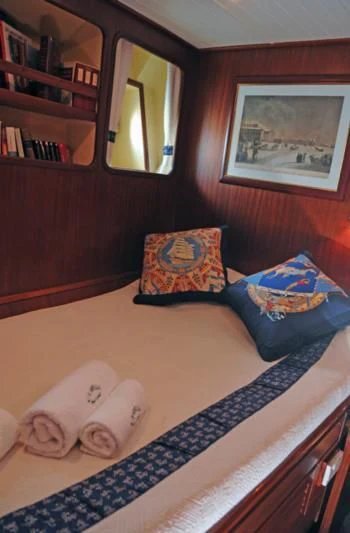 a bedroom with a blue blanket aboard OFELIA Yacht for Sale