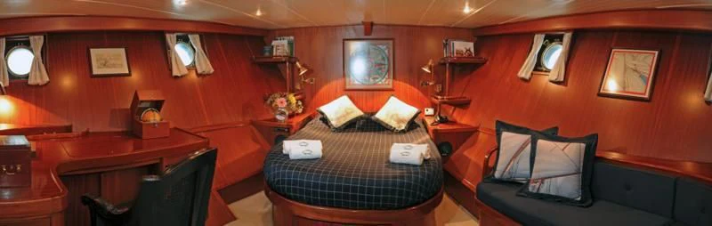 a room with a bed and desk aboard OFELIA Yacht for Sale