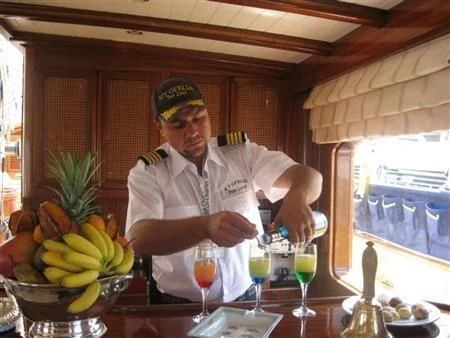 a person standing next to a table full of fruits and drinks aboard OFELIA Yacht for Sale