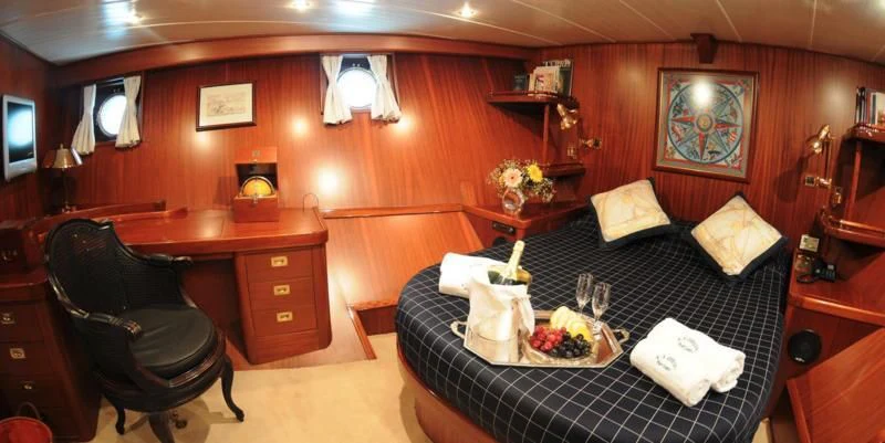 a bedroom with a bed and a chair aboard OFELIA Yacht for Sale