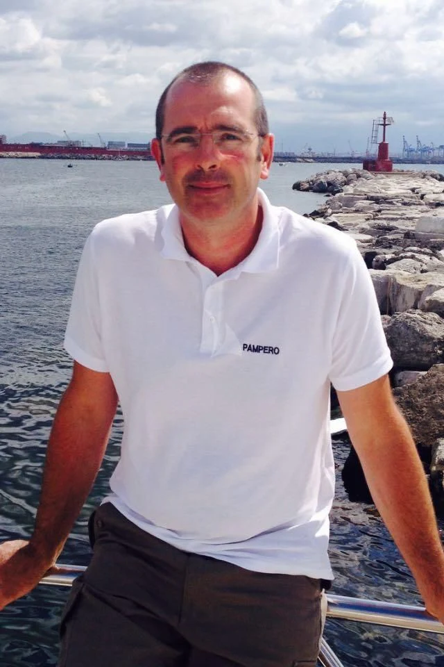 a man standing in front of a body of water aboard PAMPERO Yacht for Charter