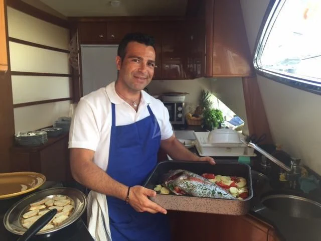 a chef holding a tray of food aboard PAMPERO Yacht for Charter