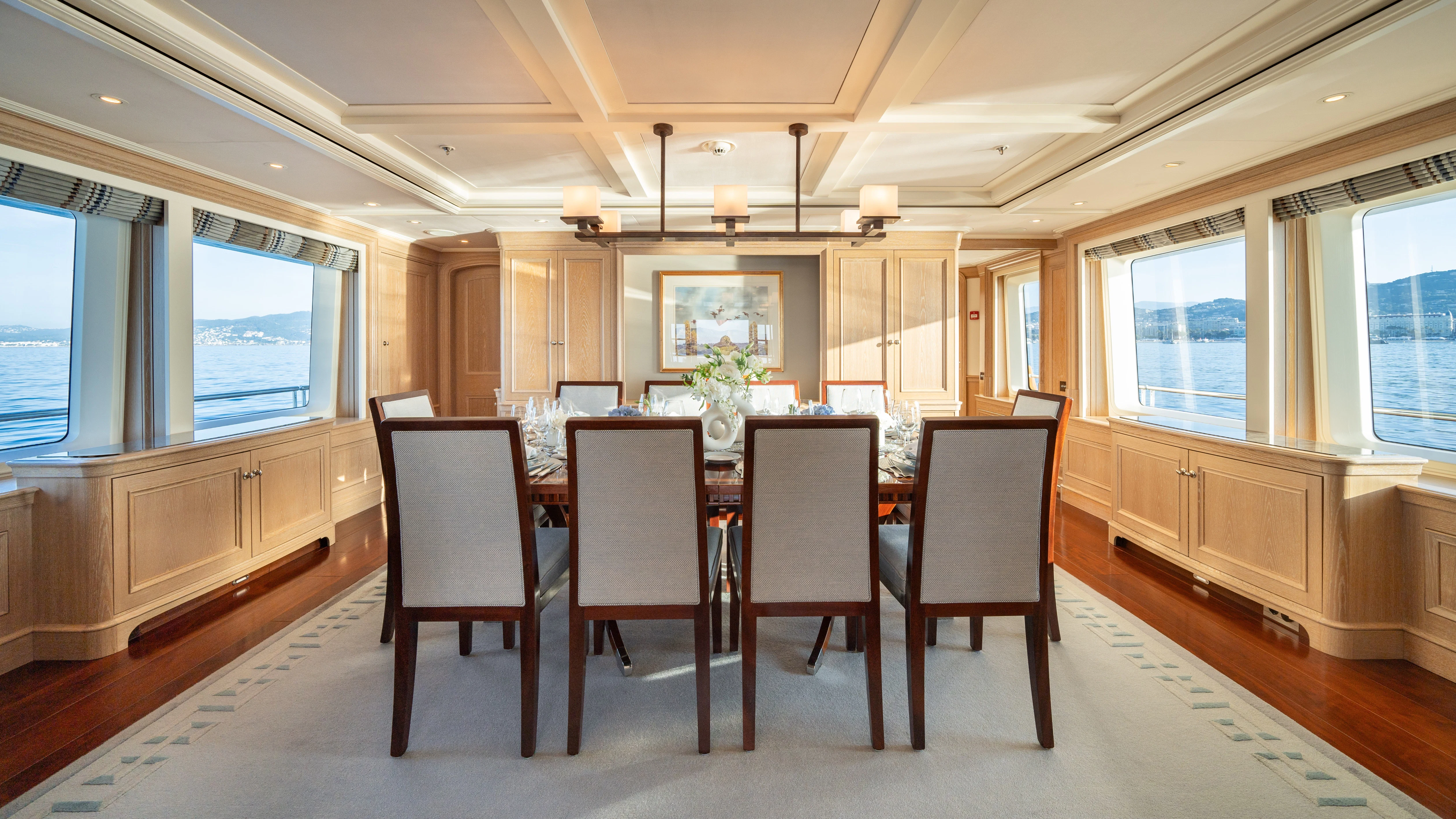 a large dining table in a large room with wood cabinets and chairs aboard FABULOUS CHARACTER Yacht for Charter
