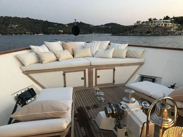 a large white bed with a table and chairs on a balcony overlooking a body of water aboard STALCA Yacht for Sale