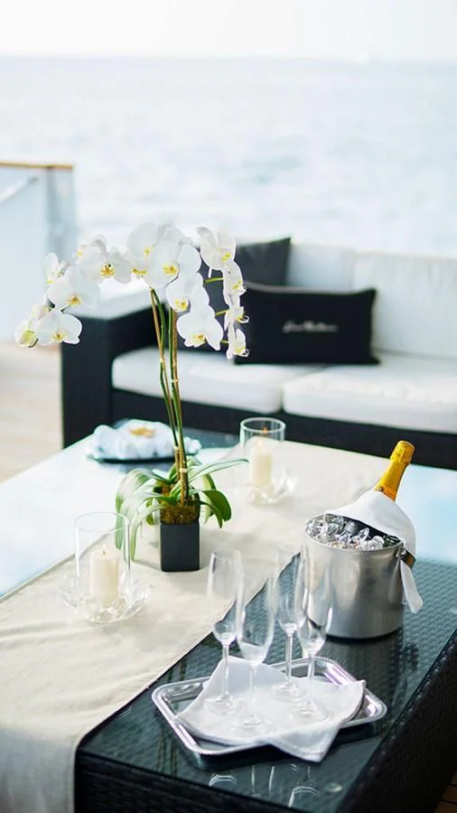 a table with a vase of flowers and glasses on it aboard GRAND ILLUSION Yacht for Sale