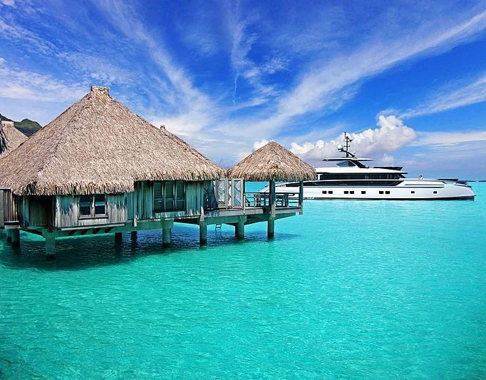 a boat in the water with Bora Bora in the background aboard STEFANIA Yacht for Sale