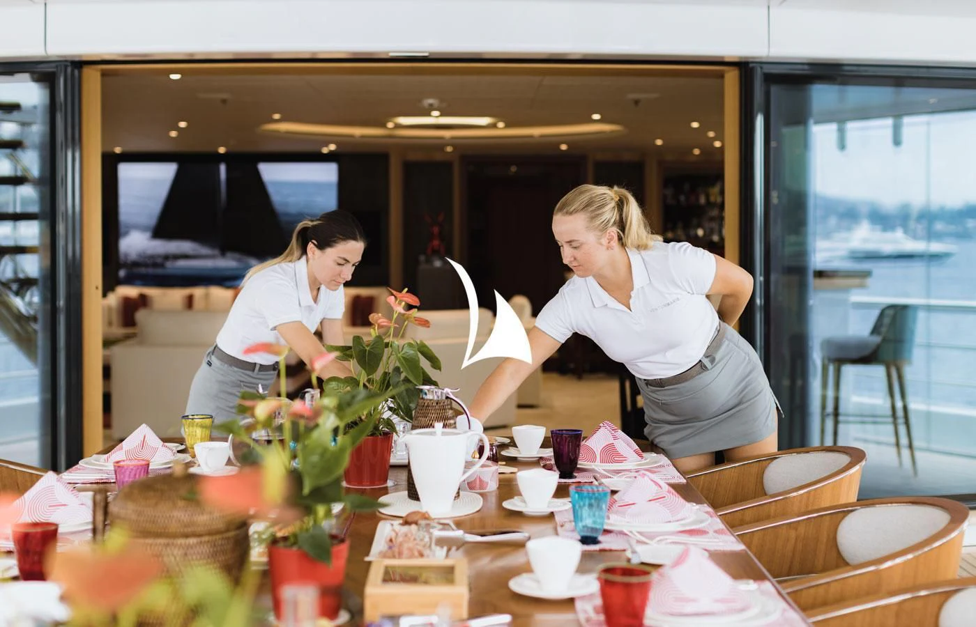 a couple of women sitting at a table with a vase of flowers aboard VENTUM MARIS Yacht for Charter