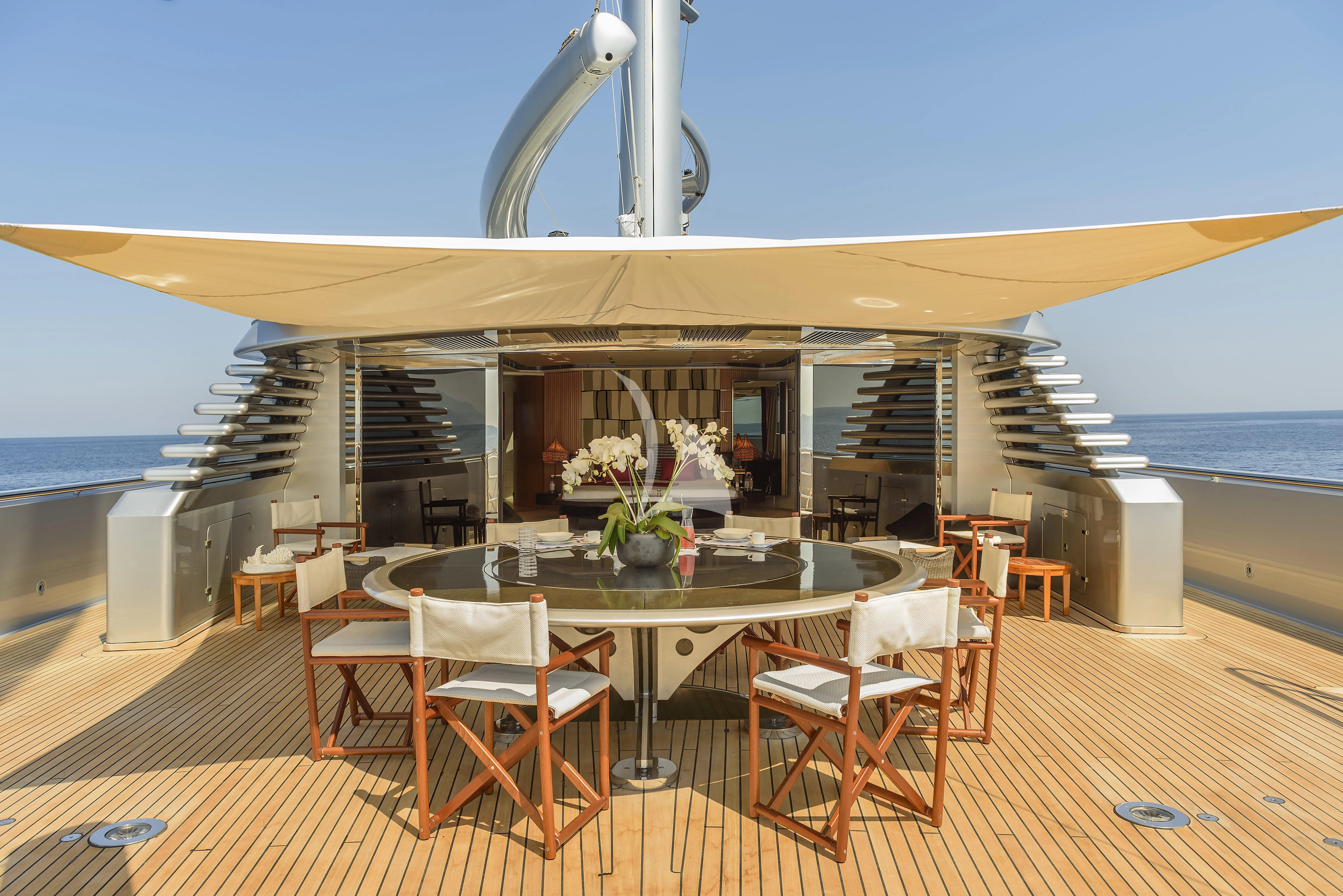 a large white building with a table and chairs on a deck aboard MALTESE FALCON Yacht for Sale