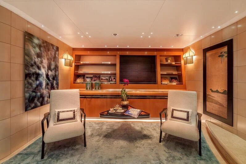 a room with a table chairs and a shelf with books aboard MALTESE FALCON Yacht for Sale