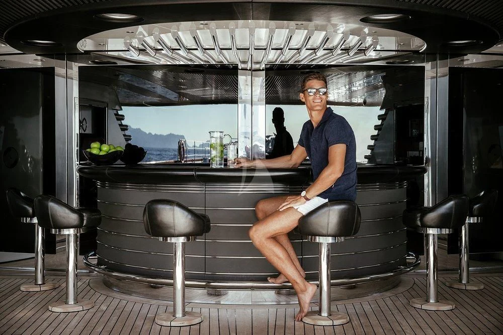 a person sitting on a stool in front of a bar aboard MALTESE FALCON Yacht for Sale