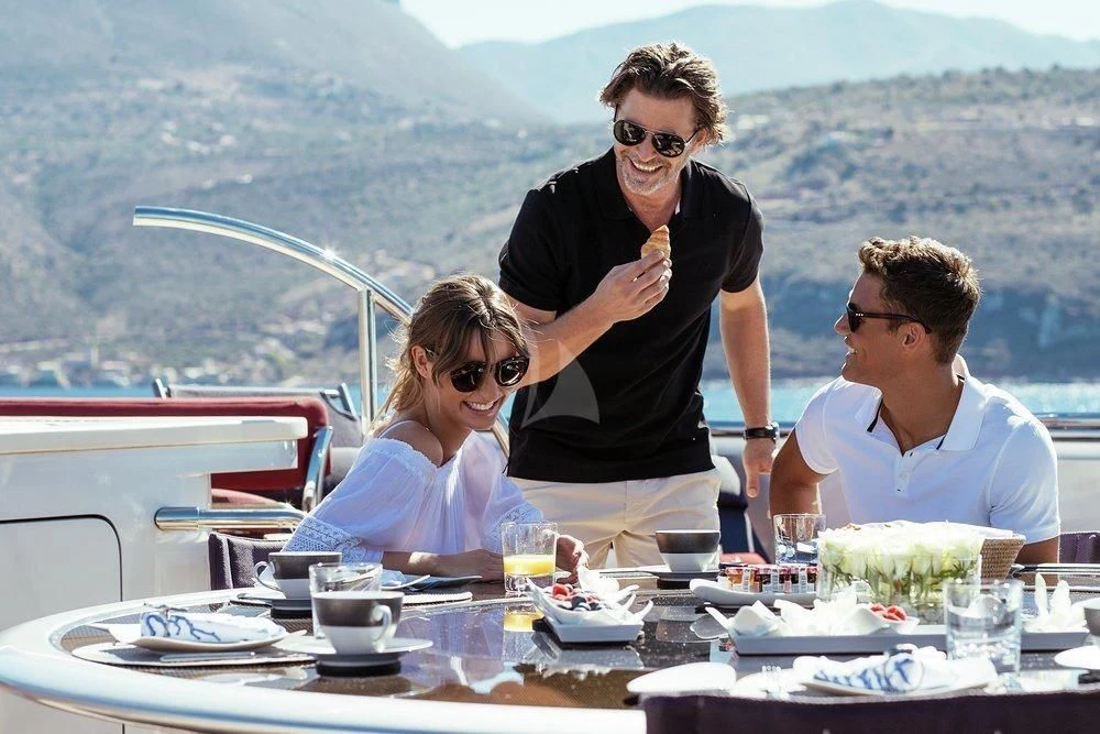 a group of people sitting at a table with food and drinks aboard MALTESE FALCON Yacht for Sale