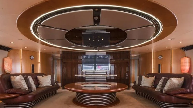 a living room with a large round table and a large mirror aboard MALTESE FALCON Yacht for Sale