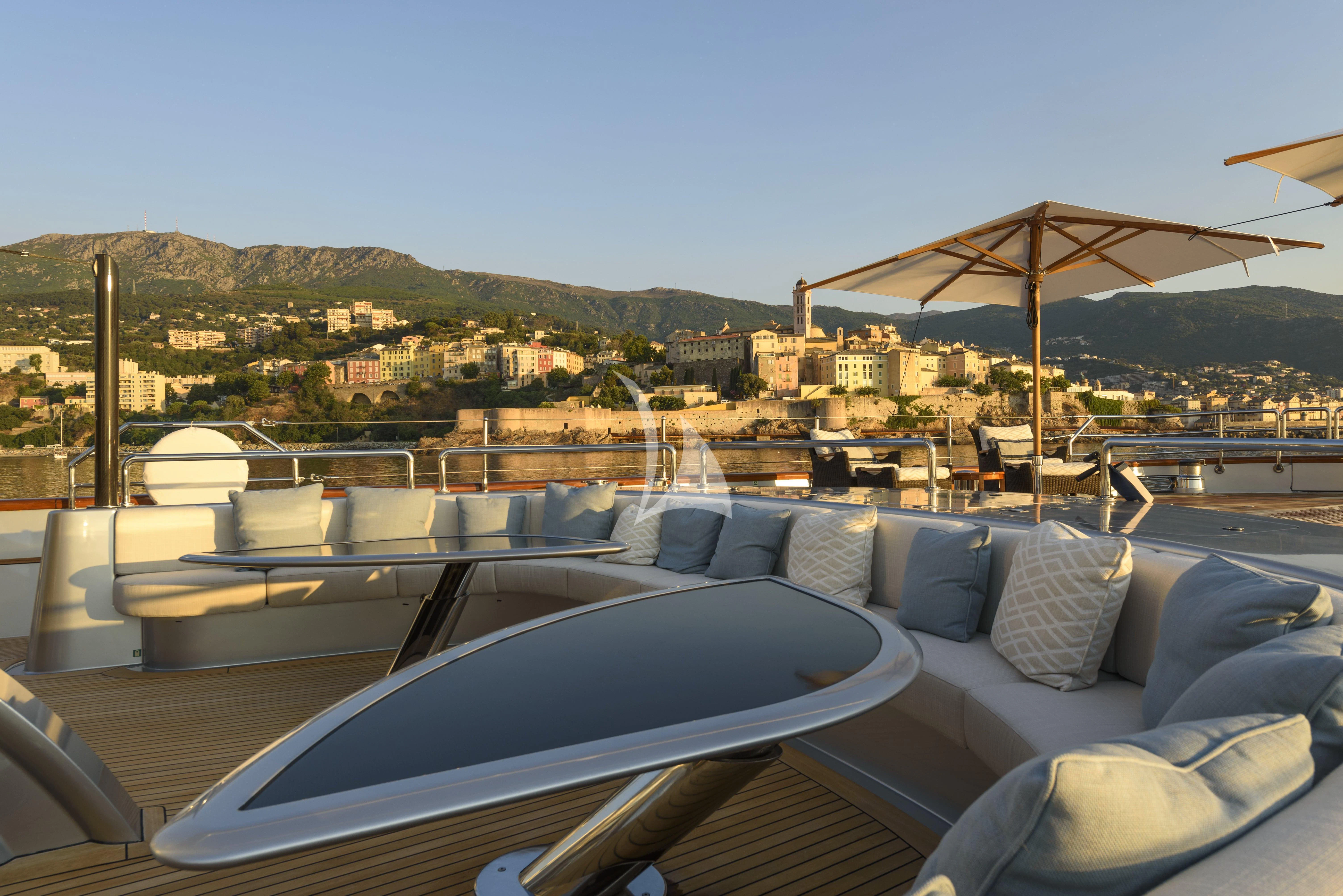 a large lounge area with a large patio and a large building in the background aboard MALTESE FALCON Yacht for Sale