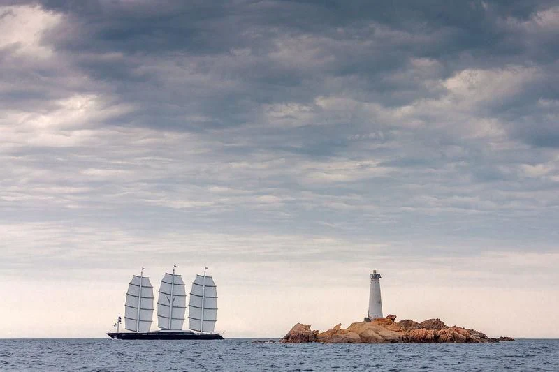 a lighthouse on a rock out in the ocean with a white tower aboard MALTESE FALCON Yacht for Sale